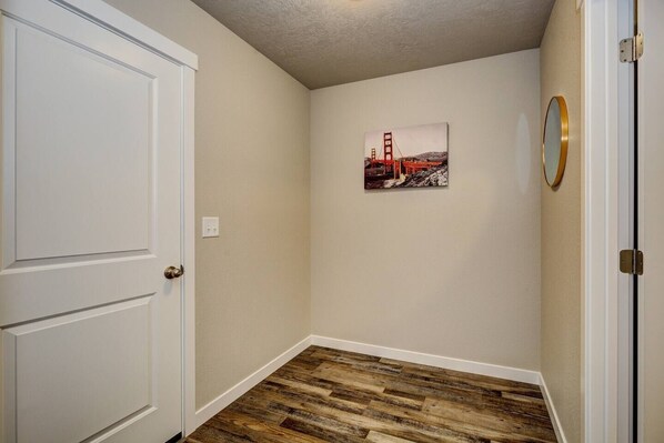Un pasillo con suelo de madera, una puerta blanca y un cuadro enmarcado del Puente Golden Gate en la pared.
