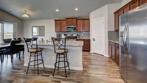 Una cocina moderna con armarios de madera, un refrigerador de acero inoxidable y una zona de bar con taburetes.
