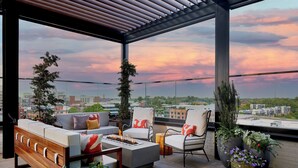 A rooftop terrace with a sofa set, chairs, a coffee table, and potted plants. - AC Hotel By Marriott Greenville (Greenville)