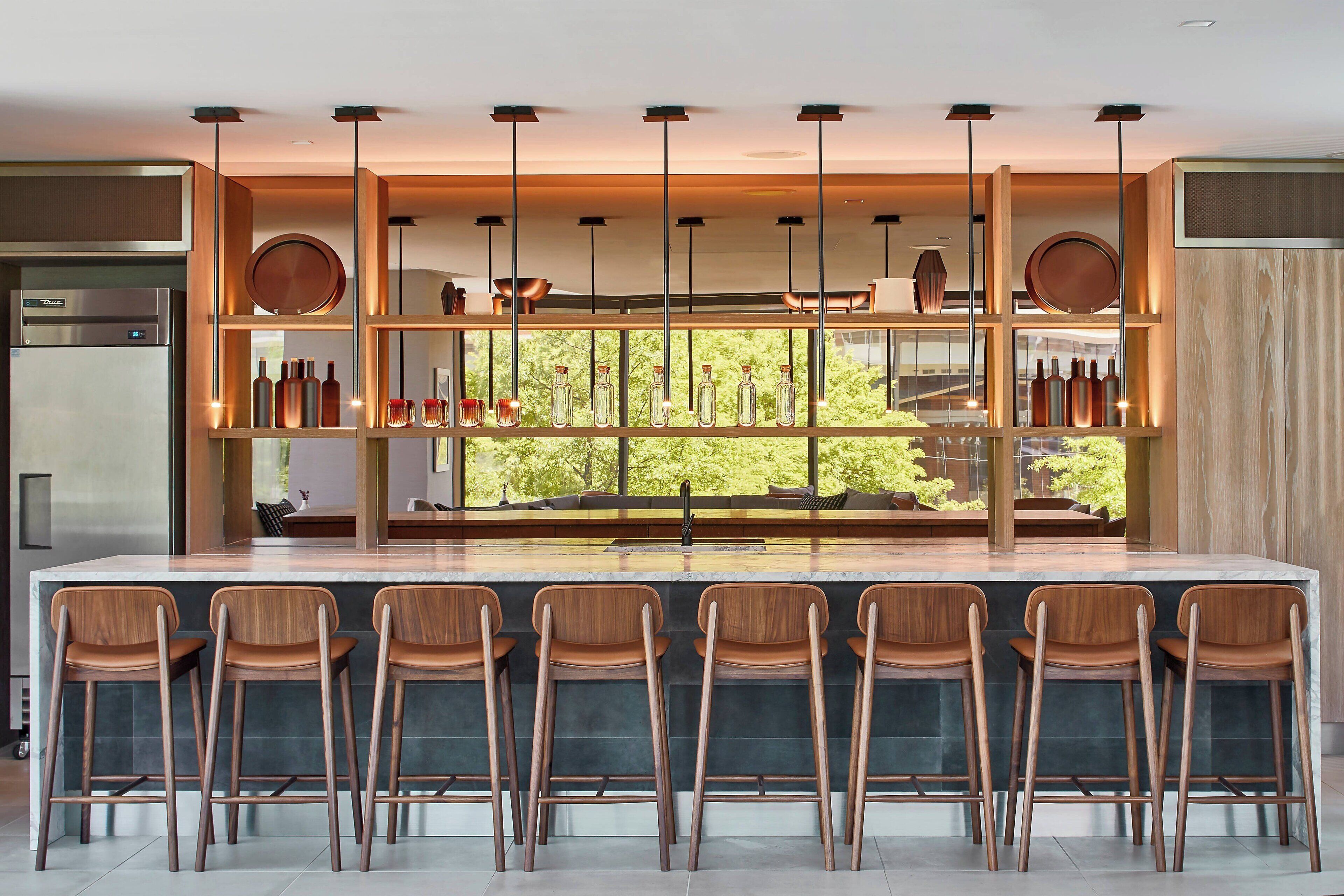 A modern kitchen with a central island, bar stools, and hanging pendant lights.