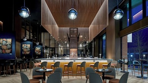 A modern bar area with wooden accents, bar stools, and pendant lighting.