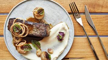 A plate of food with a steak, mushrooms, and onion rings.