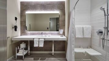 A modern bathroom with a large mirror, a white sink, and a shower area.