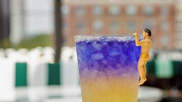 A tall glass with a gradient drink, a salt shaker, and a miniature figure on the rim.