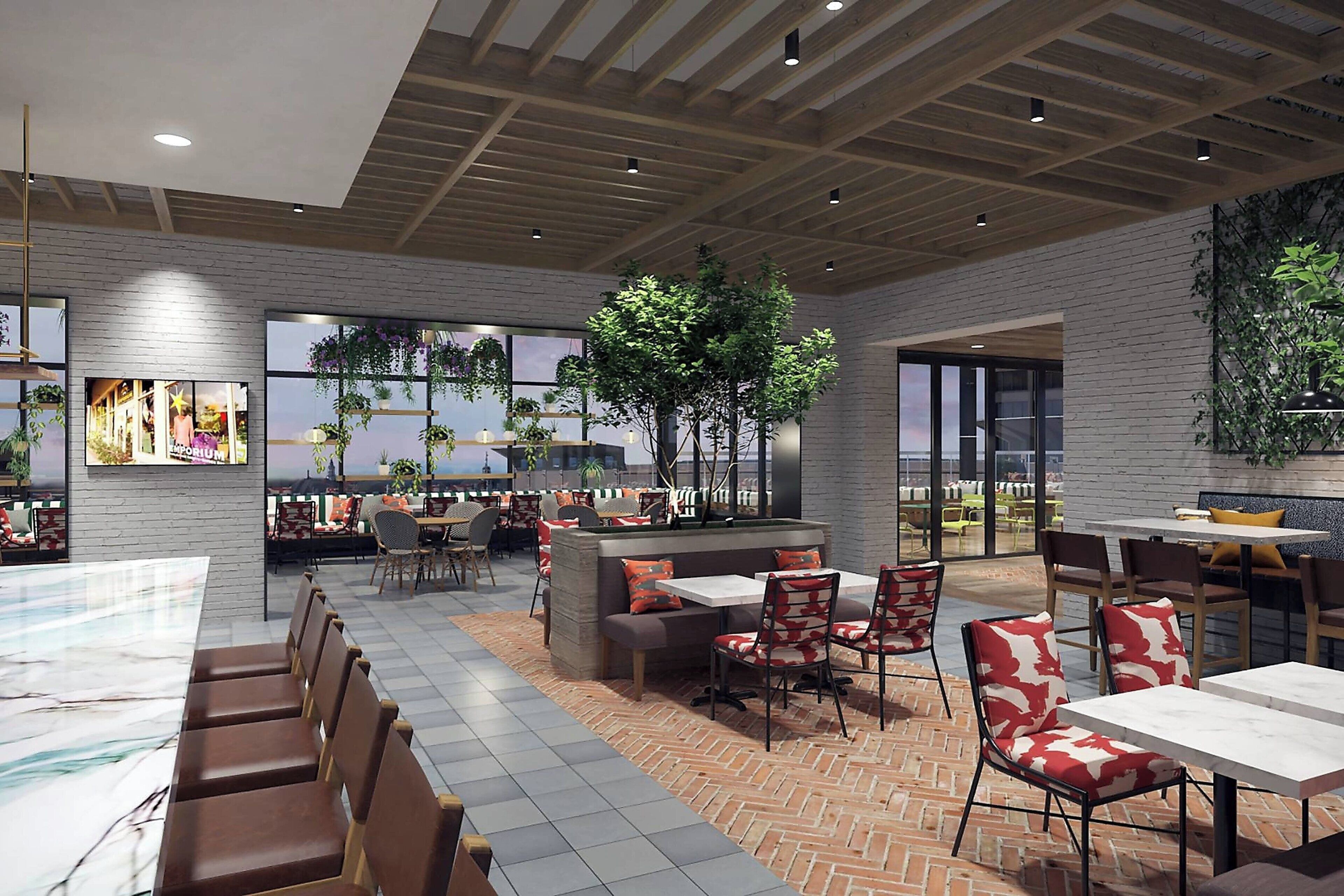 A modern indoor dining area with brick flooring, wooden ceiling beams, and large windows offering views of the cityscape.