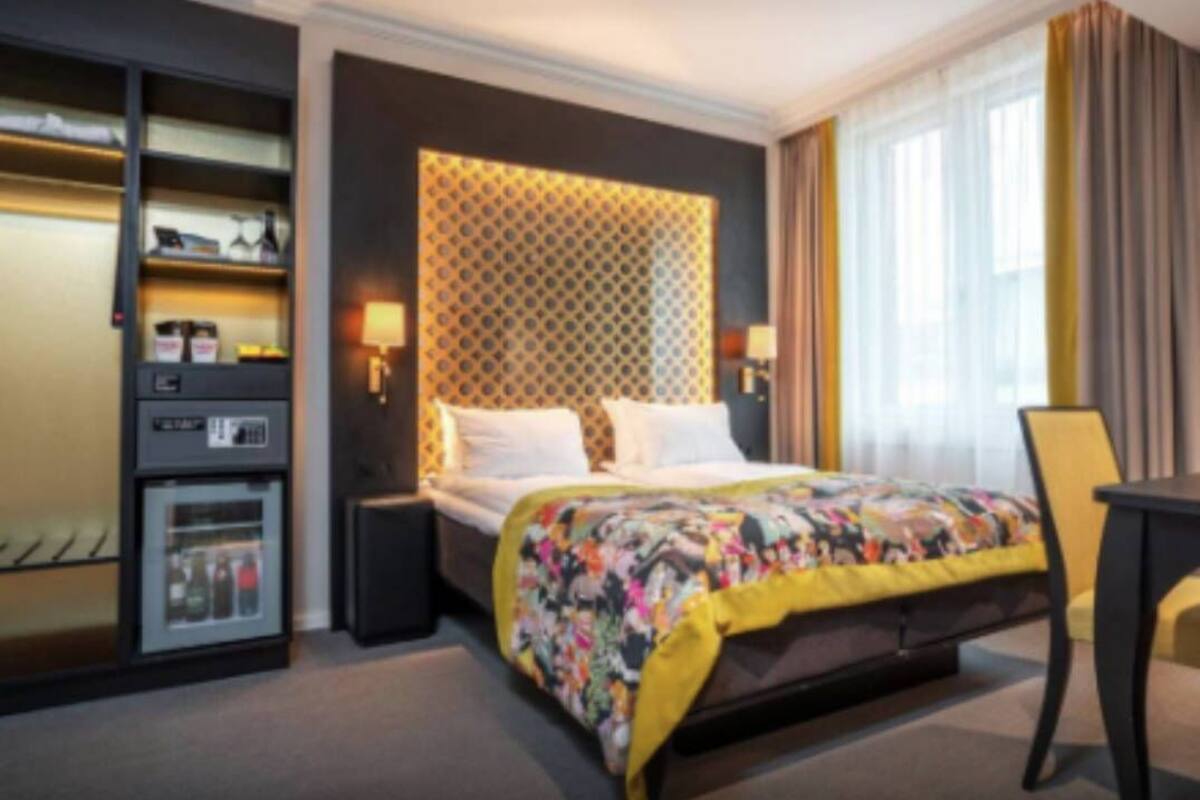 Habitación de hotel con cama, refrigerador pequeño, escritorio y silla.