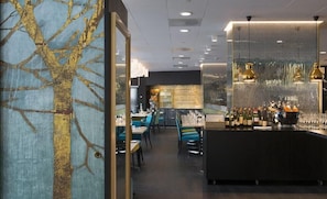 Un ristorante con zona bar, tavoli, sedie e una parete decorativa.