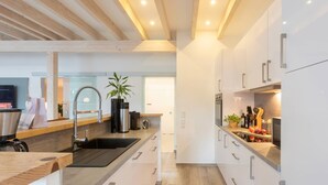 A modern kitchen with wooden beams, stainless steel appliances, and a sleek design. - Holiday Apartment "Kleine Auszeit" – Your Place to Relax (Mürlenbach)