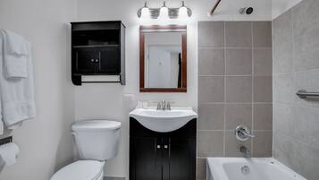 Een badkamer met toilet, wastafel en bad.