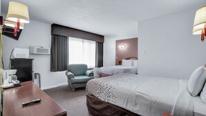 Una habitación de hotel con una cama, una silla, un escritorio con cafetera y un televisor.