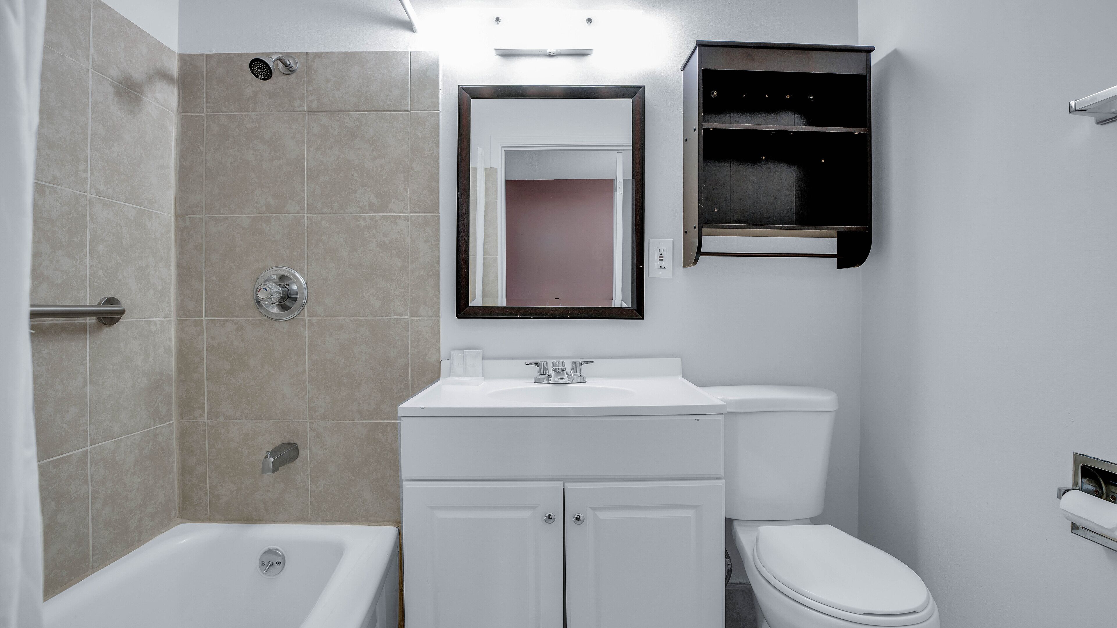 A bathroom with a bathtub, toilet, and a vanity with a mirror.