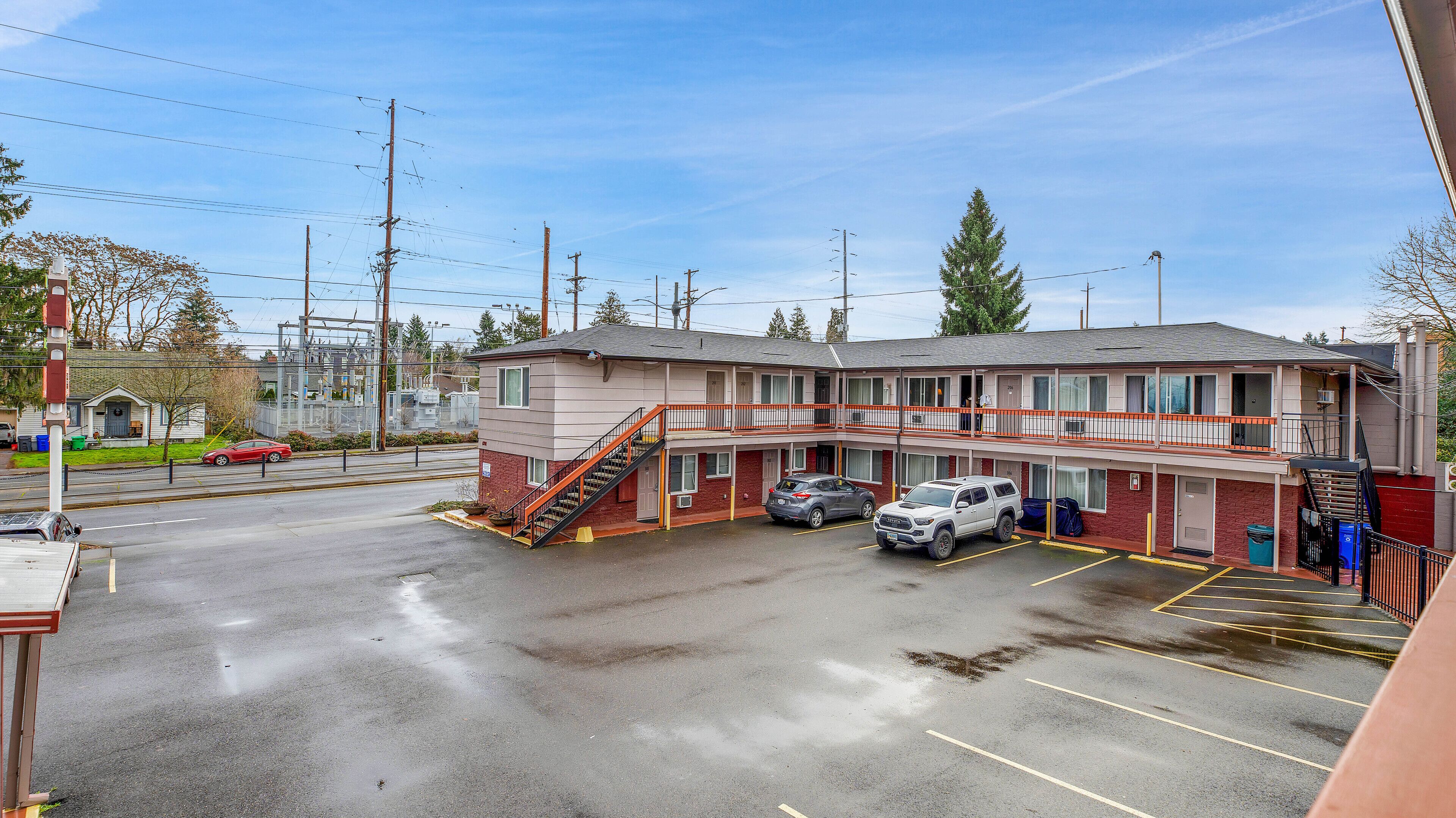 A motel with a two-story structure, a covered parking area, and a visible staircase leading to the entrance.