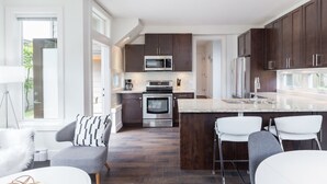 Una cocina moderna con armarios de madera oscura, electrodomésticos de acero inoxidable y una isla central con taburetes de bar.