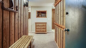 A hallway with wooden walls, a bench, a dresser, and a door with a keyhole. - Affordable Aspen - Heart of Downtown (Aspen)