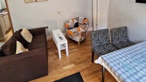 Una sala de estar con un sofá marrón, una mesa de centro blanca, un sillón estampado y un juego de sofá estampado.