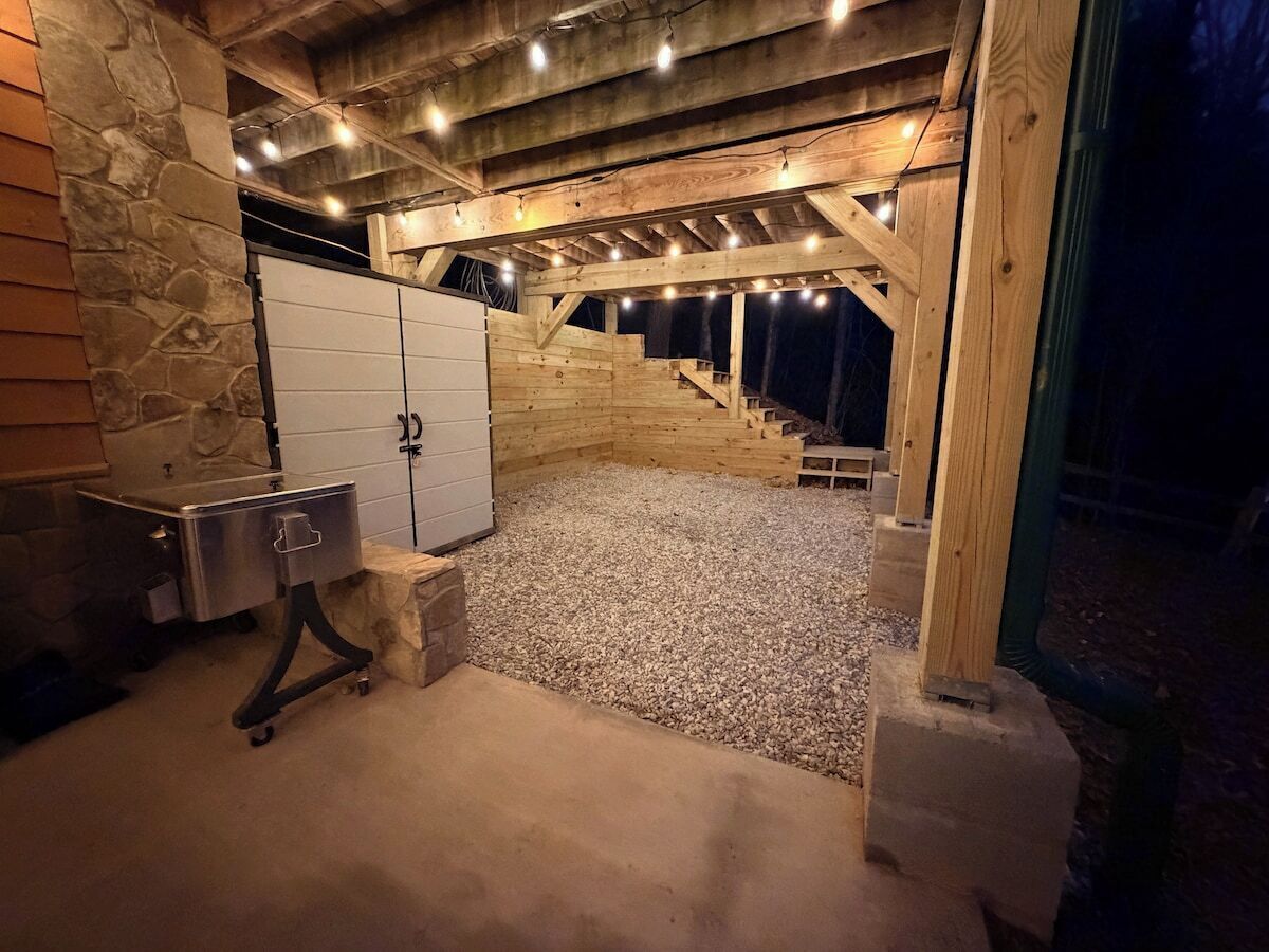 A stone wall, a metal cabinet, a wooden staircase, and a gravel floor.