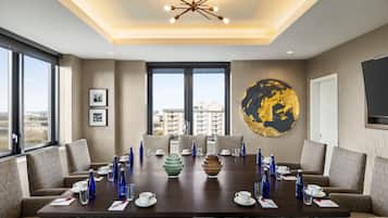 A conference room with a large table, chairs, and a city view.