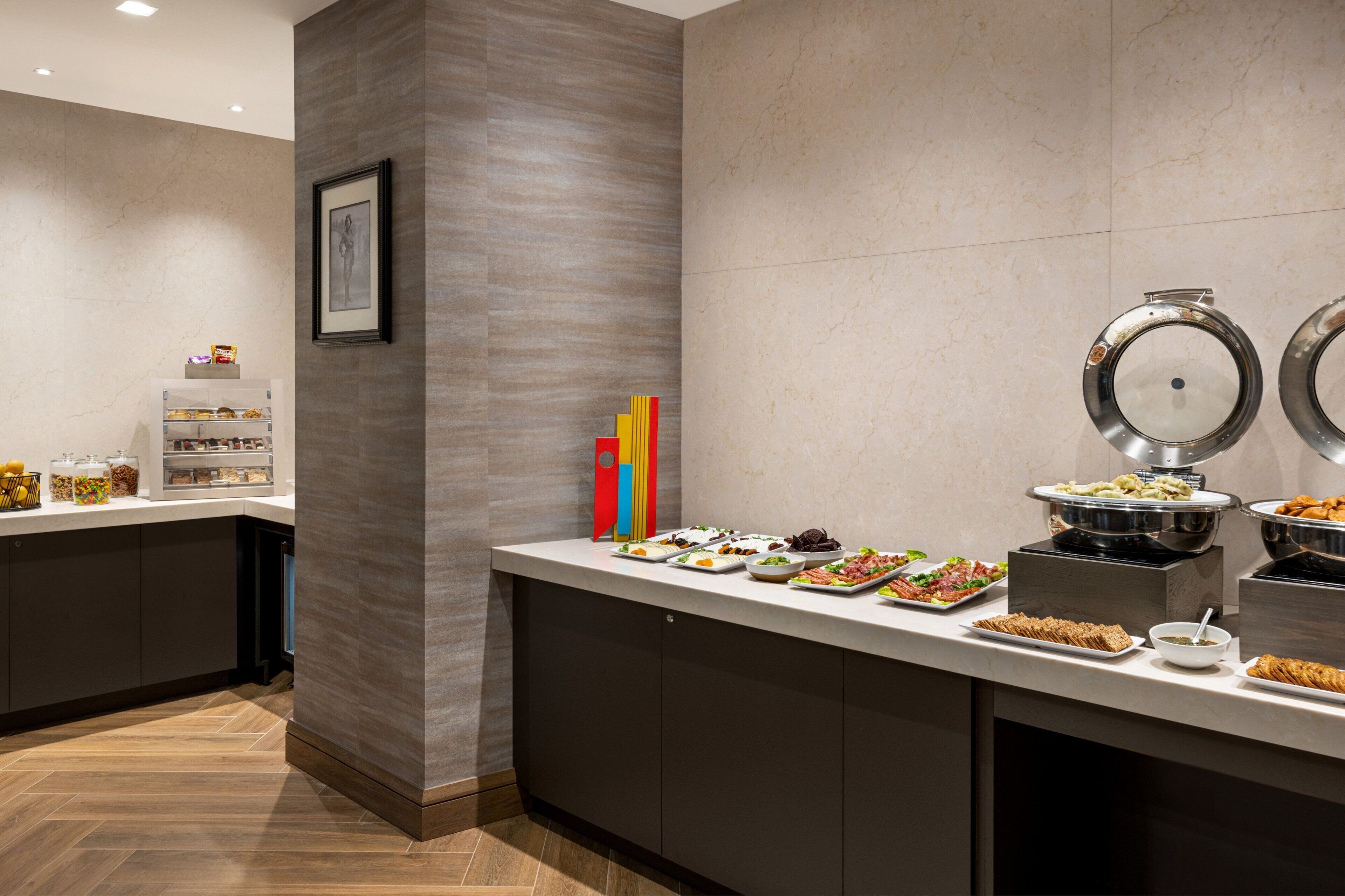 A buffet setup with various food items and a refrigerator with beverages.