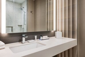 Un baño moderno con un espejo grande, un lavamanos blanco y una zona de ducha.