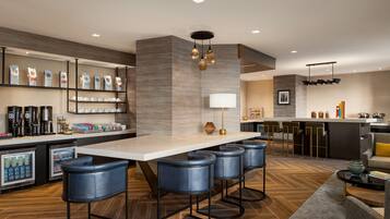 Zona de bar moderna con una mesa larga, taburetes y una estación de café.