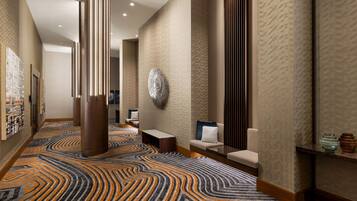 A modern hotel lobby with a patterned carpet, seating areas, and a reception desk.