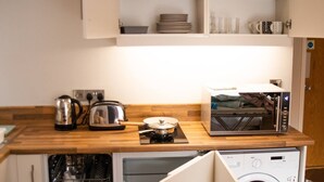 A compact kitchen with a dishwasher, microwave, and a built-in washing machine.