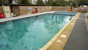 A swimming pool with a wooden deck, a lifeguard stand, and a covered seating area.