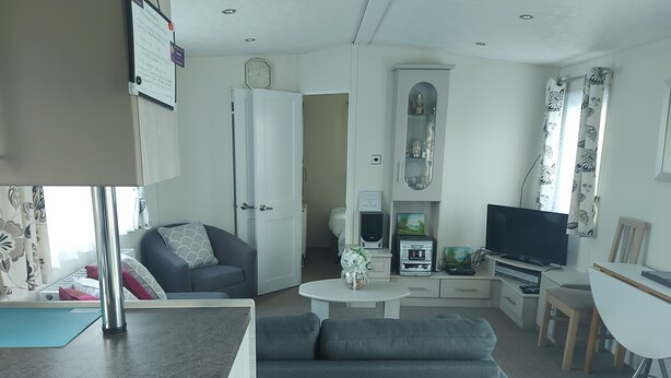 A compact living space with a sofa, a small dining table, a TV, and a kitchenette.