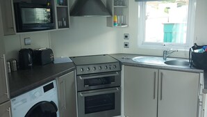 A compact kitchen with a microwave, toaster, stove, oven, and sink.