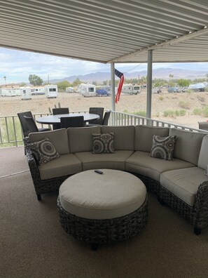 Relax in a covered outdoor seating area with a spacious L-shaped sofa and round ottoman.