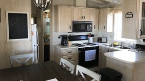 A kitchen with wooden cabinets, a black microwave, a stove, and a sink.