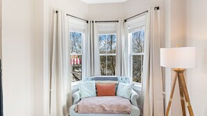 Una habitación de esquina con ventana, una silla, una lámpara de pie y una planta.