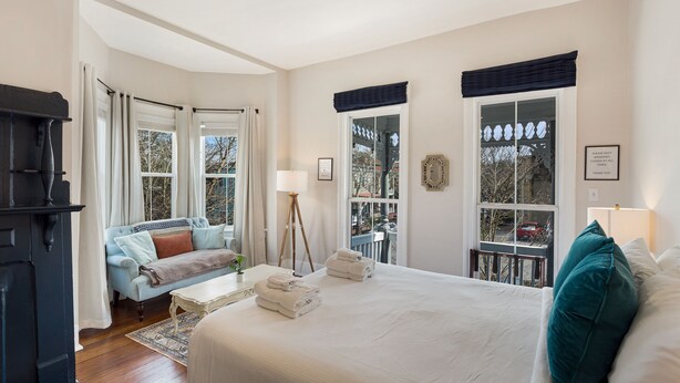 Habitación de hotel con una cama grande, un sofá, una lámpara de pie y vistas al exterior.