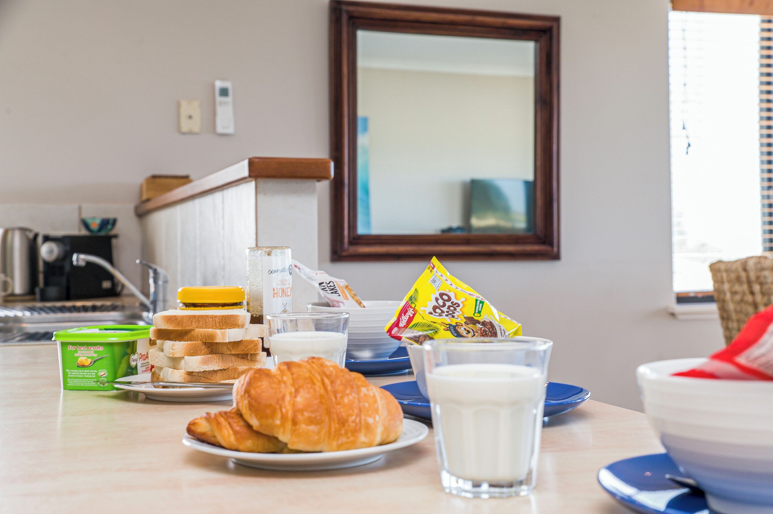 Ein Frühstückstisch mit Croissants, Milch, Müsli und einer Tüte Snacks.