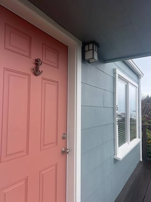 A house with a red door, a light fixture above it, and a window with shutters.