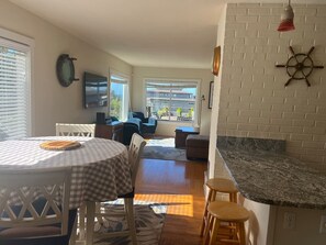 A kitchen with a round table, bar stools, a large window, and a brick wall.