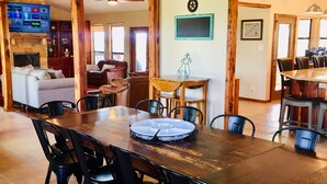 Un vaste espace dédié à la salle à manger, avec une table et des chaises en bois, une cheminée et un téléviseur permettant d’accéder à des services de diffusion en continu.