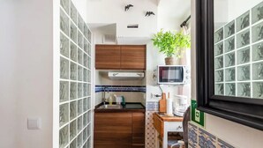 Une cuisine de taille réduite, équipée d’un four à micro-ondes, d’un évier et de meubles de rangement en bois.