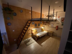 Een gezellige kamer met een houten wand, een bank, een ladder en een hanglamp.