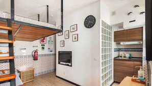Une cuisine de taille réduite, avec un plancher en bois, un téléviseur encastré et une horloge au mur.