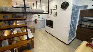 Une cuisine moderne équipée d’une cuisinière intégrée, d’un évier et d’un four à micro-ondes. On aperçoit au premier plan un banc en bois et une petite table.