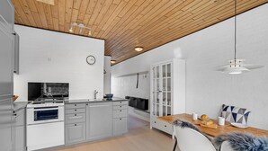 Une cuisine moderne avec des armoires blanches, un four encastré et un coin repas comprenant une table et des chaises en bois.