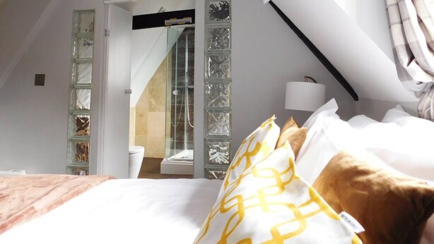 Ein Schlafzimmer mit einem Bett, einer Duschkabine aus Glas und Blick ins Badezimmer.