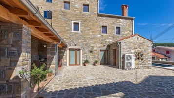 A stone building with a courtyard, featuring a small shop with an air conditioning unit.