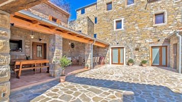 A stone building with a courtyard, wooden benches, and potted plants.