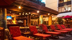 Un espace extérieur aménagé avec des fauteuils de jardin en bois et un bar en arrière-plan.