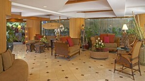 A spacious lobby with a high ceiling, wooden accents, and a variety of seating arrangements including sofas and chairs.
