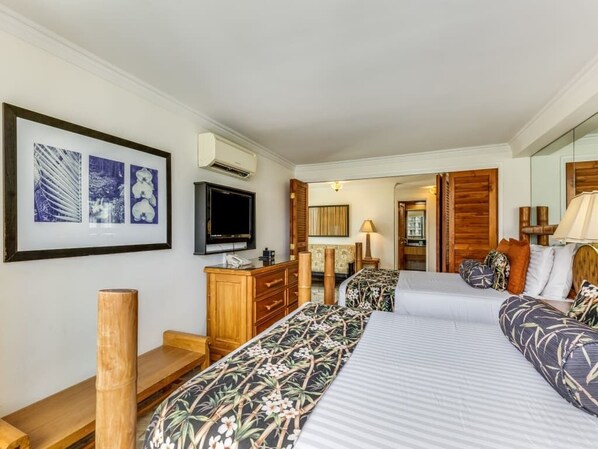 Una habitación de hotel con una cama, televisión, escritorio y espejo.
