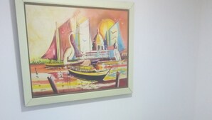 A brown sofa against a white wall with a colorful painting of a sailboat and buildings. - cerca al centro y a la playa. Cerca a todo (cartagena)