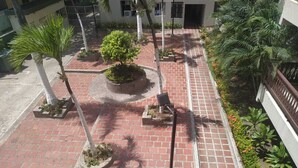 A courtyard with a brick pathway, palm trees, and potted plants. - cerca al centro y a la playa. Cerca a todo (cartagena)